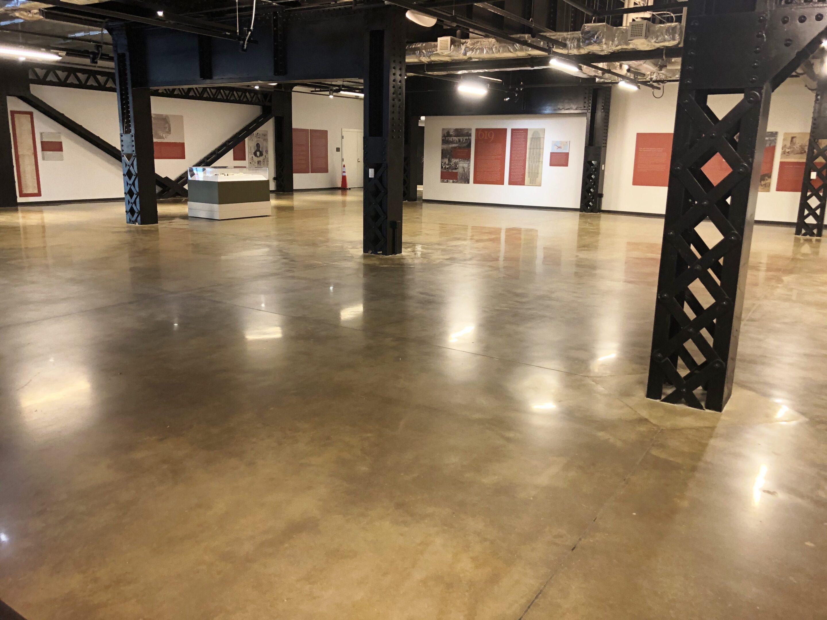 A large room with concrete floors and black pillars.