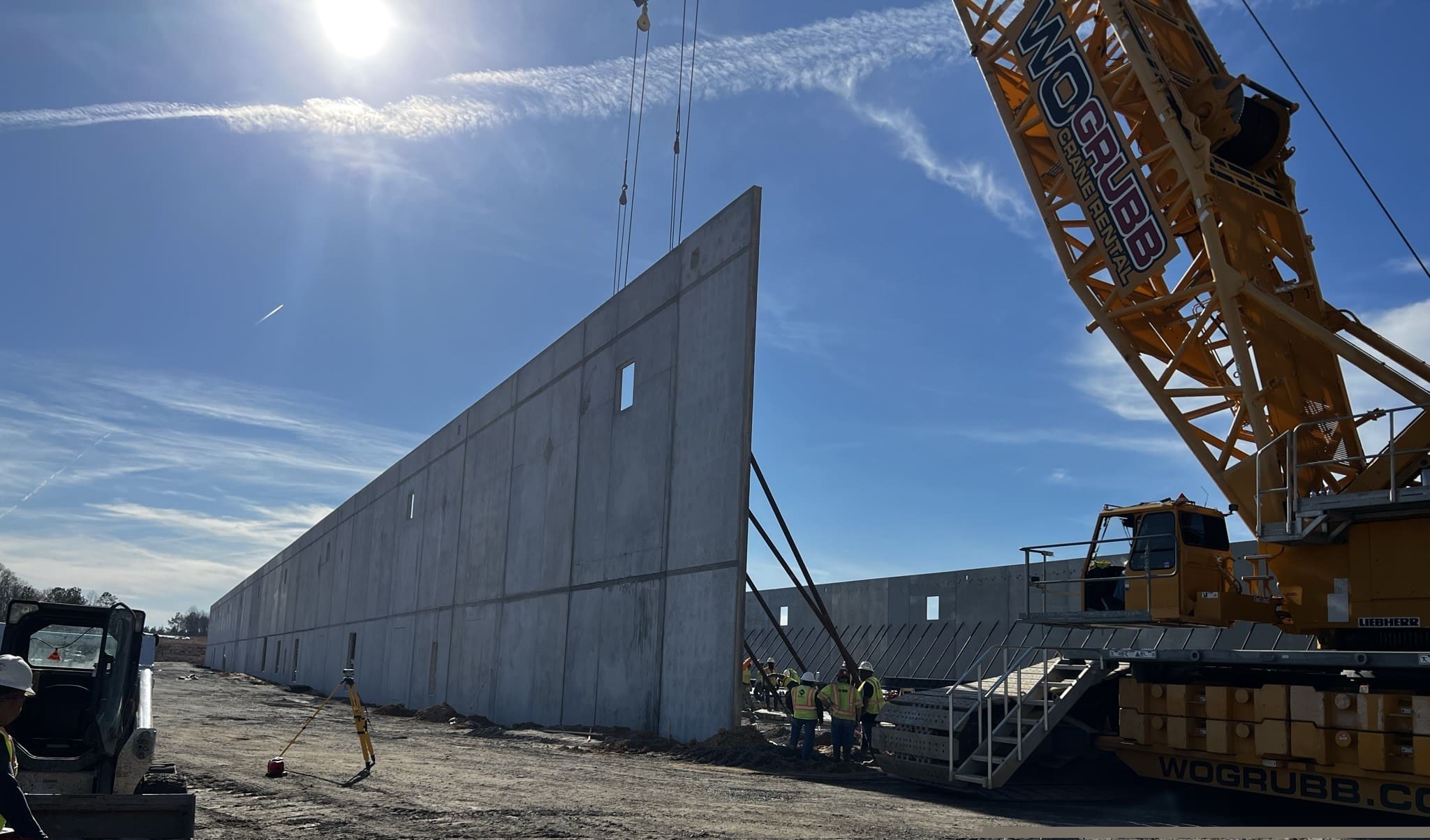 A crane is lifting a large concrete wall.