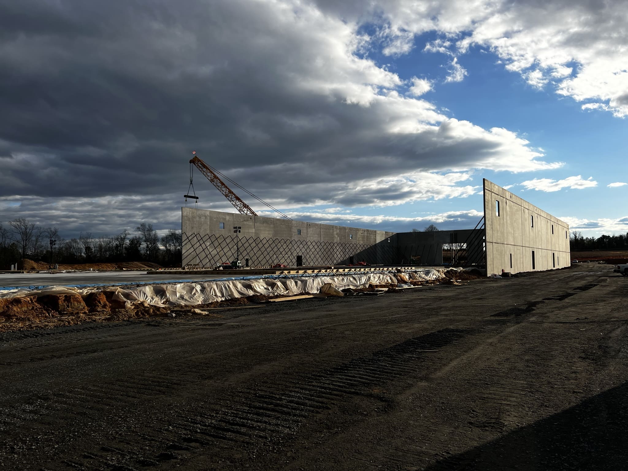 A large concrete wall under construction in the middle of a field.